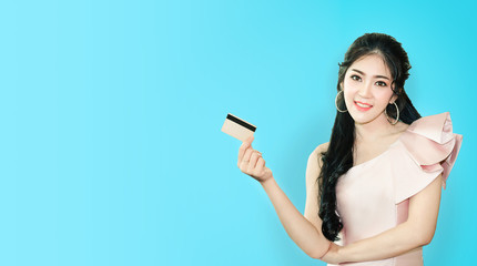 Naklejka premium Portrait of young asian woman showing credit card with copy space blue background