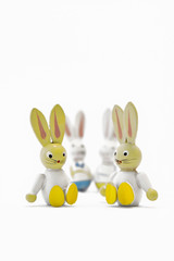 Two toy easter bunnies sitting side by side with their father and mother in the background. Happy family. Portrait format.