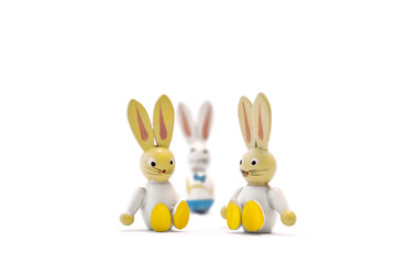 Two toy easter bunnies sitting side by side with their father in the background. Single parent family. Landscape format.