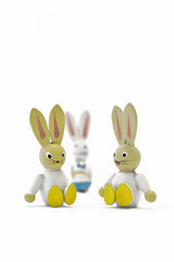 Two toy easter bunnies sitting side by side with their father in the background. Single parent family. Portrait format.