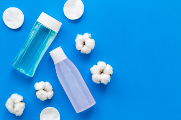 skin care cosmetics with facial tonic, mycelial water and cotton pads on blue background top view mockup