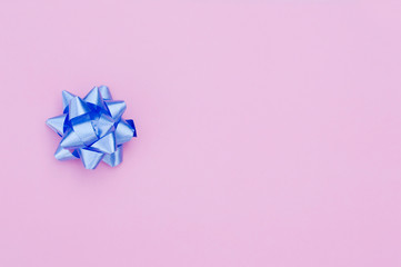 blue gift bow on a pink background, space for text