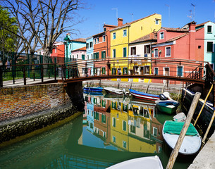 Fototapeta na wymiar Burano, Venice, Italy: view on a canal with its coloured houses reflecting on the water