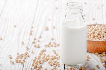 Non-dairy alternative Soy milk or yogurt in glass bottle on white wooden table with soybeans in bowl aside