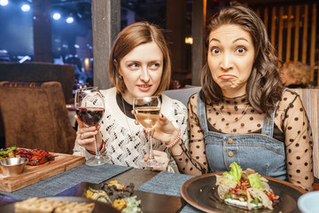 Two girls friends chatting and drinking wine in a restaurant in a nightclub. Concept of friendship and food and drinks