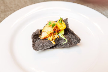 Haute cuisine dish of cuttlefish ink with eel and vegetables on a plate. Creative and minimalistic delicacy concept