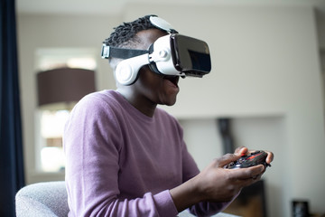 Excited Teenage Boy Playing Video Game At Home Wearing Virtual Reality Headset
