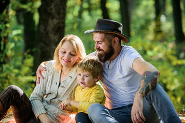 Mother father and little son sit forest picnic. Good day for spring picnic in nature. Explore nature together. Family day concept. Mom dad and kid boy relaxing while hiking in forest. Family picnic