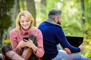 Modern life. Happy loving couple relaxing in park with mobile gadgets. Modern people always...