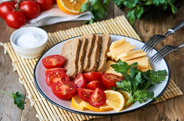 Plate of cherry tomatoes, cheese and rye bread on a wooden background