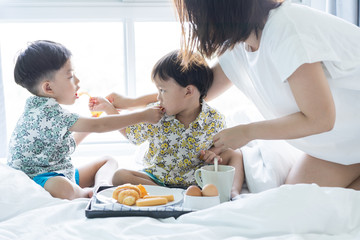 Brothers are sharing breakfast on the bed in the morning.