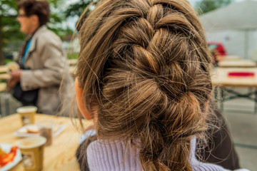 Girls brown hair plaited into one big plait at back side of her head closeup.