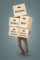 Mann trägt einen großen Stapel Umzugskartons