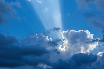Fototapeta na wymiar Beautiful sun rays shining through storm clouds remainings on blue sky.