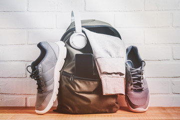 Green backpack with sportswear and sneakers. The concept of fitness or running