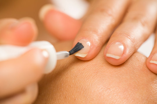 woman applying a nail polish on her fingernails