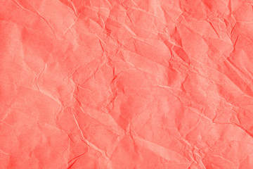 Trendy coral colored textured background. Crumpled orange-pink craft paper. Flat lay.