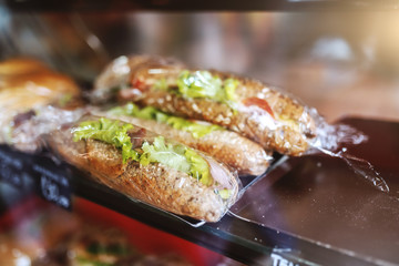 Close up of delicious fresh sandwiches in foil ready for sale. Bakehouse interior.