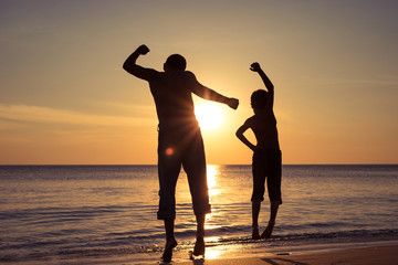 Father and son  playing on the beach at the sunset time.