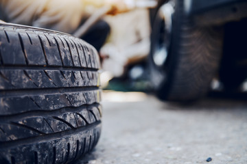 Auto mechanic changing tire while crouching at workshop. Selective focus on tire.