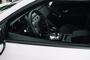 black steering wheel in luxury white automobile in car showroom