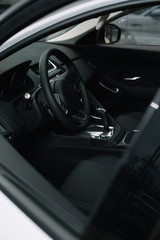 selective focus of black steering wheel near gear shift handle in luxury car