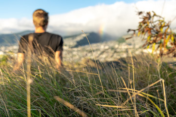Young male hiker sitting on the summit of Diamond Head Crater in Honolulu on the Island of Oahu,...