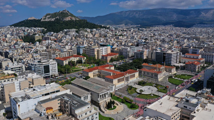 Fototapeta premium Aerial drone photo of trilogy neoclassic buildings, Academy of Athens, University and public library and Lycabettus hill at the background, Athens, Attica, Greece