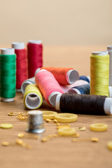 selective focus of colorful thread coils, safety pins and buttons isolated on beige