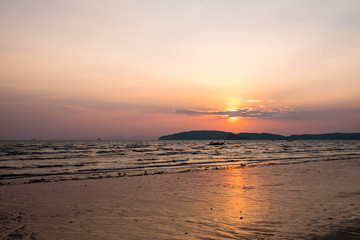 Panoramic photo of beautiful sunset over the sea, sun goes behind the mountain.