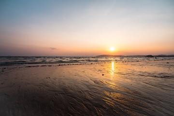 Panoramic photo of beautiful sunset over the sea, sun goes behind the mountain.