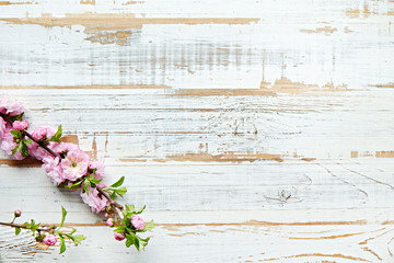 Fototapeta premium Bunch of spring flowering branches with a lot of white-pink blossoms on wooden background. Rustic composition w/ spring flowers on vintage textured wood table. Close up, copy space, top view.