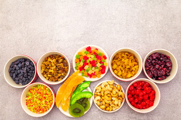 Dried and candied fruit and cashew nuts. Assorted in ceramic bowls on a stone background. Healthy vegetarian (vegan) food concept, copy space, top view.