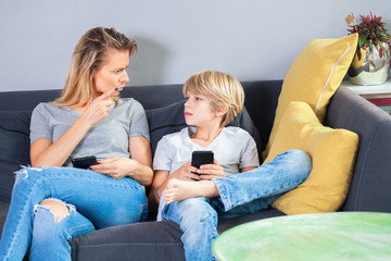 unhappy and angry mother holding  lesson to the son,complaining that he spends so much time with smart phone. concept of Internet addiction