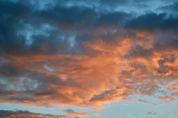 Dark blue and bright red Cumulus rain clouds illuminated by the evening sun. Clouds are coming and foretell rain and bad weather. Weather forecast, meteorology. Nature and atmosphere.