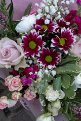 A top down view of bunches of multi-coloured flowers and roses for sale at a local market, including pink, red and purple