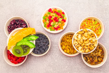 Dried and candied fruit and cashew nuts. Assorted in ceramic bowls on a stone background. Healthy vegetarian (vegan) food concept, copy space, top view.