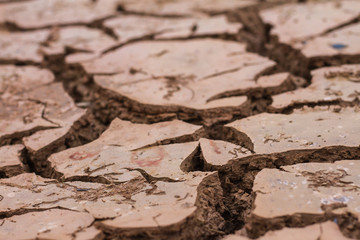 Deep cracks earth in the red land as a symbol of hot climate and drought.