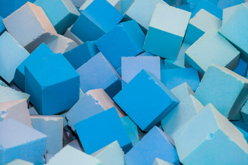 Many blue soft blocks in a kids' pool at a playground. Bright multi-colored soft cubes, geometric toys. Multicolored background.