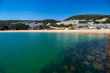 Rocks under transparent blue water with mountains in background