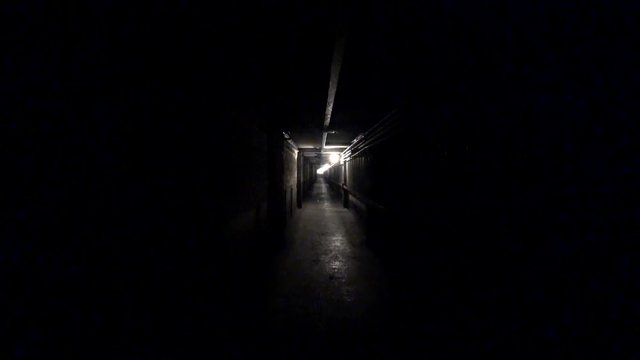 Worker walk through a dark corridor at a metallurgical plant. POV, action camera shot.
