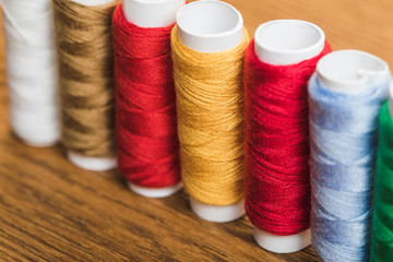 colorful cotton thread coils in row on wooden surface