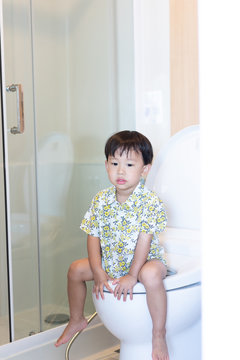 A boy is sitting on toilet.