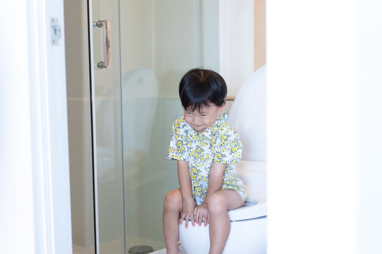 A boy is sitting on toilet.