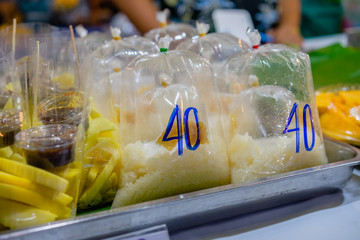 sweet rice and fruits in plastic bags selling on the street market 