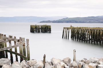 Old derelict wooden jetty pier in sea coast town of Helensburgh Argyll