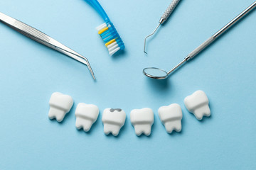 White tooth with caries on blue background  and dentist tools mirror, hook.