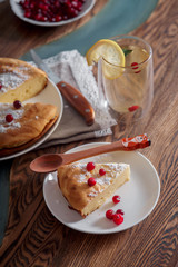 Cheesecake with cranberries and sugar, green tea and lemon on wooden table