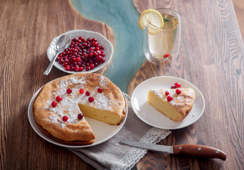 Cheesecake with cranberries and sugar, green tea and lemon on wooden table