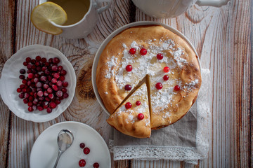 Cheesecake with cranberries and sugar, green tea and lemon on wooden table